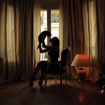 Boudoirfoto zu Hause. Frau sitzt auf dem Sessel mit Katze in Händen.