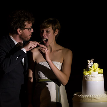 Bräutigam gibt der Braut ein Stück Hochzeitstorte zu probieren. Hochzeit in Italien.